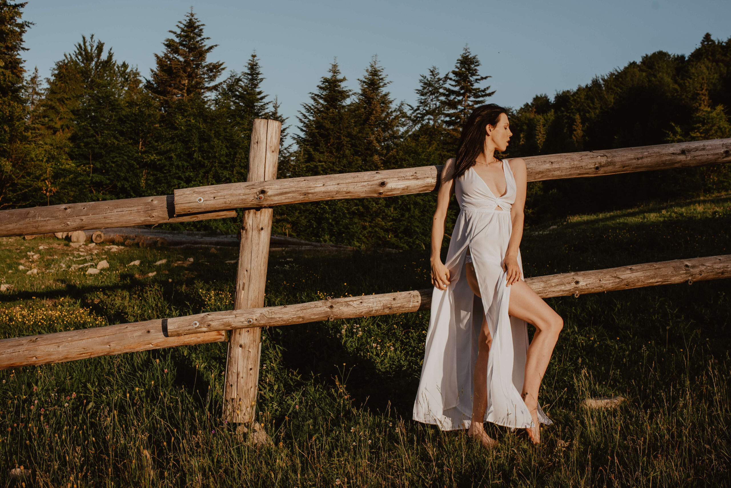 Eine natürliche und authentische Braut in einem zarten, fließenden Kleid, die den Sonnenaufgang in der Nähe einer rustikalen Pferdekoppel genießt und sich von der Schönheit der unberührten Natur inspirieren lässt.
